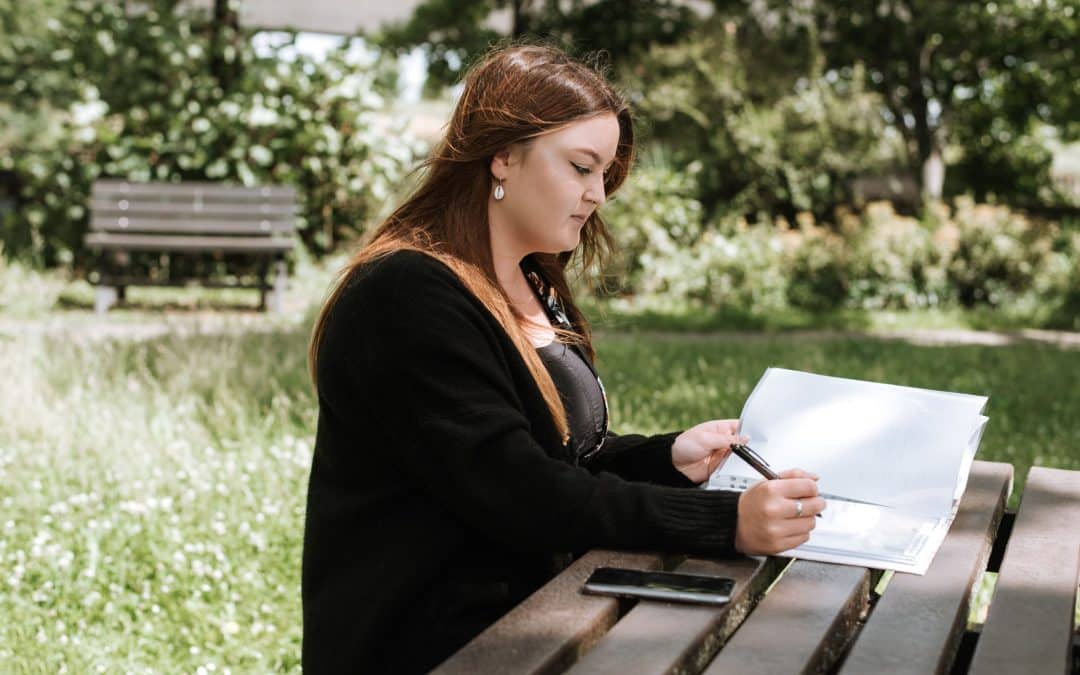 estate planning mistakes ot avoid woman writing in notebook with phone in park